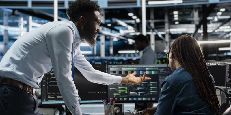 Data center system administrators setting up machine learning systems handling information. IT professionals in office training neural networks node trees to improve server farm operations