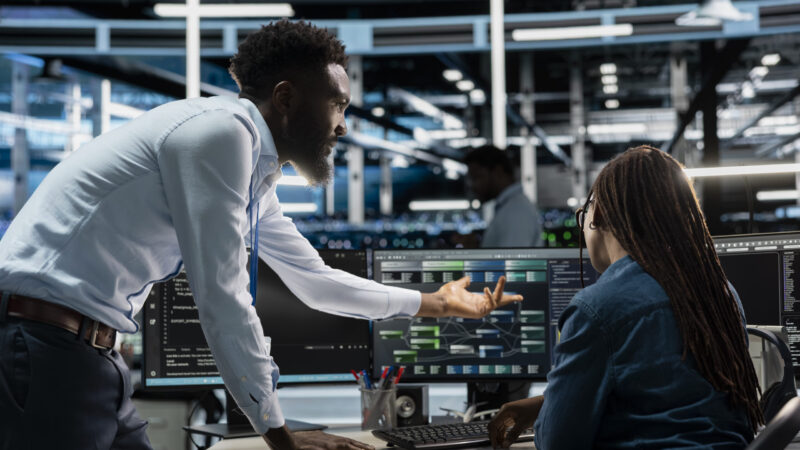 Data center system administrators setting up machine learning systems handling information. IT professionals in office training neural networks node trees to improve server farm operations