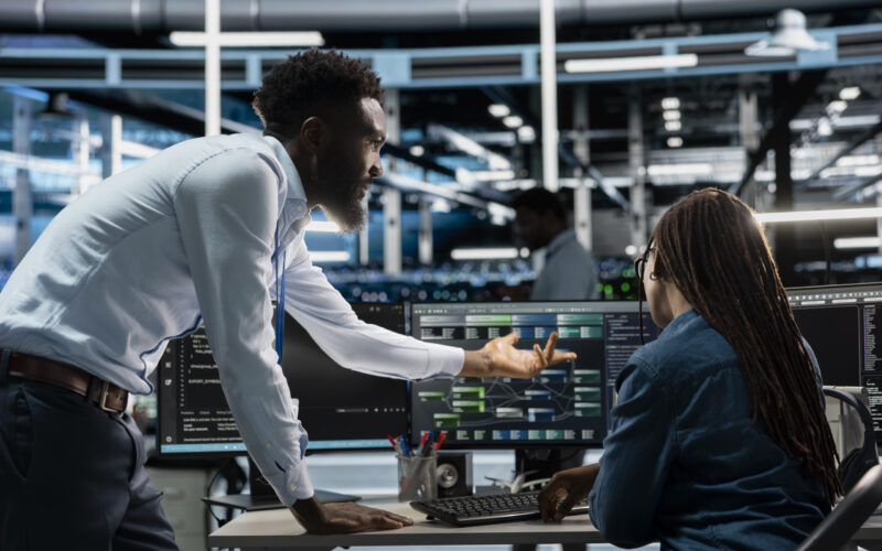 Data center system administrators setting up machine learning systems handling information. IT professionals in office training neural networks node trees to improve server farm operations