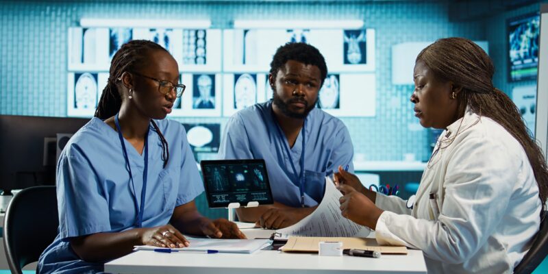 Team of male and female african american medical staff discussing diagnostic results with a medic expert in a modern cabinet. Advanced technology and healthcare services at clinic. Camera B.